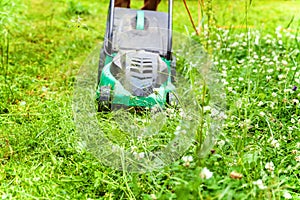 Man cutting green grass with lawn mower in backyard