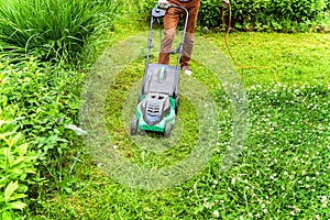 Man cutting green grass with lawn mower in backyard