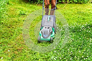 Man cutting green grass with lawn mower in backyard