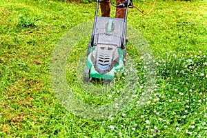 Man cutting green grass with lawn mower in backyard