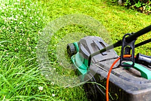 Man cutting green grass with lawn mower in backyard