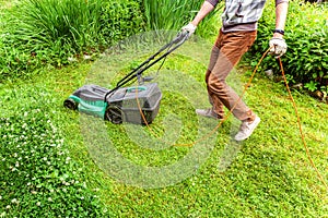 Man cutting green grass with lawn mower in backyard