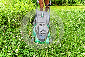 Man cutting green grass with lawn mower in backyard