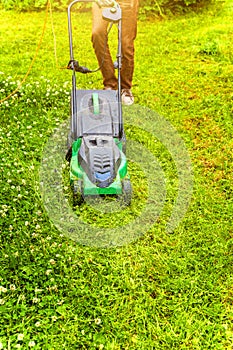 Man cutting green grass with lawn mower in backyard. Gardening country lifestyle background. Beautiful view on fresh