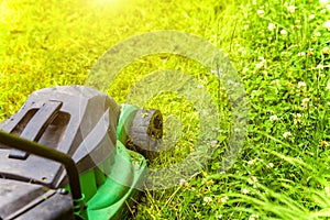 Man cutting green grass with lawn mower in backyard. Gardening country lifestyle background. Beautiful view on fresh green grass