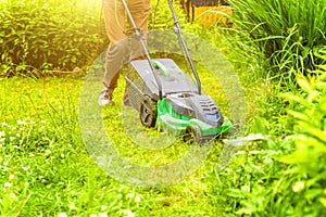 Man cutting green grass with lawn mower in backyard. Gardening country lifestyle background. Beautiful view on fresh green grass