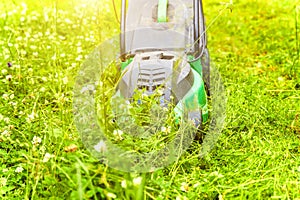 Man cutting green grass with lawn mower in backyard. Gardening country lifestyle background. Beautiful view on fresh green grass