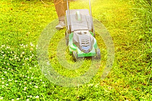 Man cutting green grass with lawn mower in backyard. Gardening country lifestyle background. Beautiful view on fresh green grass