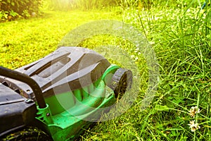 Man cutting green grass with lawn mower in backyard. Gardening country lifestyle background. Beautiful view on fresh green grass