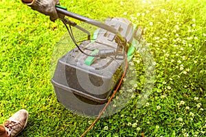 Man cutting green grass with lawn mower in backyard. Gardening country lifestyle background. Beautiful view on fresh green grass