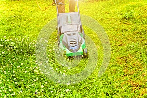 Man cutting green grass with lawn mower in backyard. Gardening country lifestyle background. Beautiful view on fresh green grass