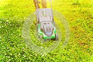 Man cutting green grass with lawn mower in backyard. Gardening country lifestyle background. Beautiful view on fresh green grass