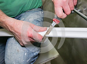 Man is cutting gypsum baseboard with utility knife. Maintenance repair works renovation in the flat . Restoration indoors. Drywall