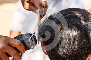 Man is cutting hill-man's hair