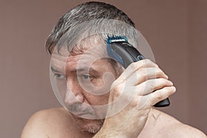 Man cutting his own hair with a clipper