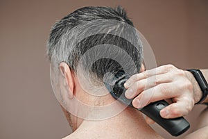 Man cutting his own hair with a clipper