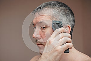 Man cutting his own hair with a clipper