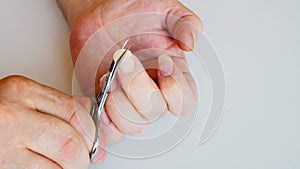 Man cutting long nails. Trembling male hands clumsily cut very long fingernails with small scissors. Male manicure. Untidy nails