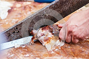 man cutting meat with big metal knife