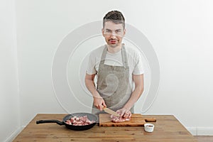 Man cutting meat with a knife on a cutting board. Wooden table. Fresh pork meat, frying pan