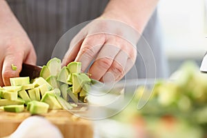 Man cutting mellow avocado on cutting board, inspiration to cook tasty dinner