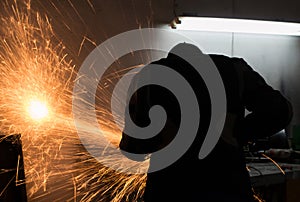 Man cutting metal, fly sparks over the working table