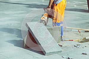 Man cutting paving slab with circular saw for repairing