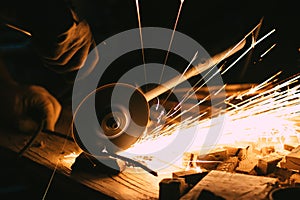 Man cutting a piece of metal with an angle grinder with sparks jumping out of it