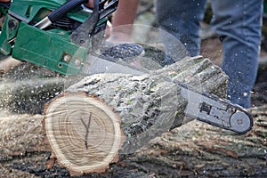 Man cutting piece of wood with chain saw.