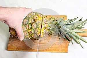 Man cutting pineapple on a wooden board