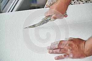 Man cutting polystyrene foam heat insulation with old retractable utility knife, closeup detail