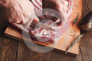 Chef cutting rack of lamb on wooden board