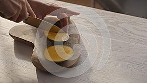 Man cutting ripe mango on olive board on white oak table