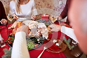 Man cutting roasted turkey on a table background. Family enjoying autumn holidays. Thanksgiving dinner concept.