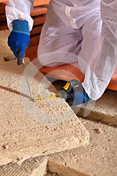 Man cutting rockwool panel to fit in thermal insulation layer photo