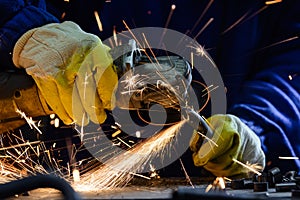 Man cutting steel pipe with an angle grinder producing hot sparks