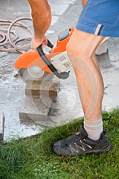 Man cutting stone tiles with a circular saw. vertical