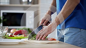 Man cutting tomatoes and lettuce preparing fresh vegetable salad, healthy eating