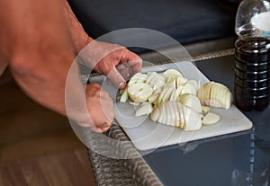 man cutting white onion with knife on board