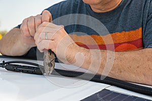 Man cutting a wire tie for a solar panel connection on a recreational vehicle.