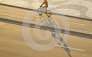 Man cycling along the wave pattern sidewalk of Portuguese pavement, Copacabana beach, Brazil