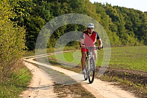 Man is cycling in autumn forest