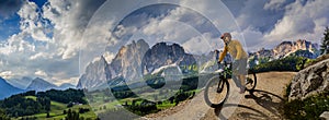 Man cycling on electric bike, rides mountain trail. Man riding on bike in Dolomites mountains landscape. Cycling e-mtb enduro