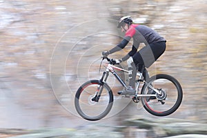 Man cycling fast with mountainbike in a forest in fall