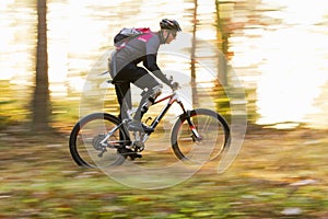 Man cycling fast with mountainbike in a forest in fall photo