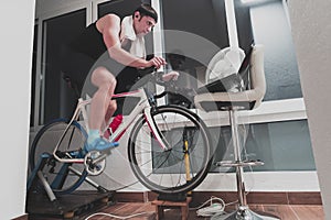 Man cycling on the machine trainer he is exercising in the home at night playing online bike racing game