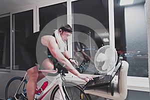 Man cycling on the machine trainer he is exercising in the home at night playing online bike racing game