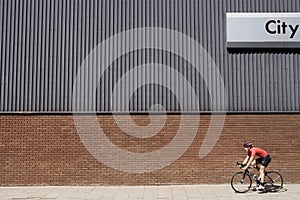 Man cycling past building with `City` written on side