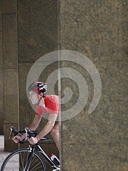 Man Cycling Between Pillars In Portico