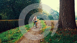 Man cycling on a trail in the autumn park. forest, sad mood, moving camera